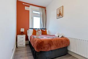 ein Schlafzimmer mit einem Bett mit einer orangefarbenen Decke in der Unterkunft Stylish 2 Bed Apartment near Central London in London