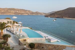 a swimming pool next to a body of water at Panormos Village Hotel in Mykonos