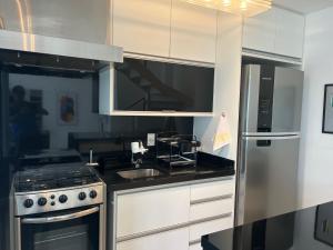 uma cozinha com armários brancos e um frigorífico de aço inoxidável em Duplex Morumbi Luxo em São Paulo