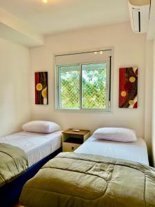 two beds in a room with a window at Duplex Morumbi Luxo in Sao Paulo