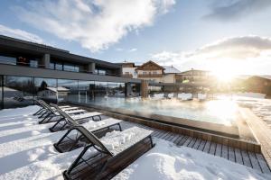 a building with a swimming pool in the snow at Hotel Viertler in Avelengo