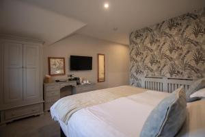 a bedroom with a bed and a desk and a television at Briery Wood Hotel in Ambleside