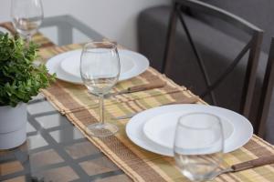 a table with white plates and glasses on it at Close to Railway Station Apartment on the 7th Floor in Katowice by Renters in Katowice