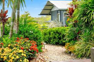 einen Garten mit Blumen und Palmen und ein Haus in der Unterkunft The Sanctuary - Family Retreat - Noosa Hinterland in North Arm