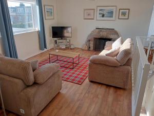 a living room with two chairs and a fireplace at Stonesthrow Elie, 2 Mins to Beach, Free Parking in Elie
