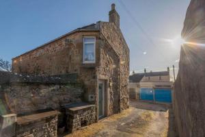 un ancien bâtiment en briques avec une fenêtre et un banc dans l'établissement Stonesthrow Elie, 2 Mins to Beach, Free Parking, à Elie