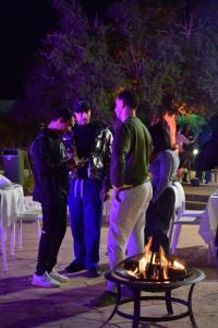 a group of people standing around a fire at night at Lunja Village - Agadir in Taghazout