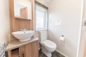ein Badezimmer mit einer weißen Toilette und einem Waschbecken in der Unterkunft Tastefully decorated lodge on popular holiday park, easy access to Lakes and Dales and free parking in Carnforth + 17 Fotos