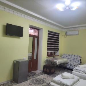 ein Wohnzimmer mit einem TV an der Wand in der Unterkunft Hotel Dilnura in Samarkand