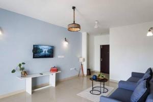 - un salon avec un canapé bleu et une table dans l'établissement Blue Pearl Apartment by JadeCaps Nr Airport 3bhk, à Devanhalli