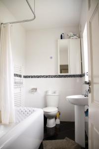 a white bathroom with a toilet and a sink at Idyllic Cottage in Jubilee Park in London