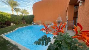Villa with private pool cancun elsokhna 93 في العين السخنة: مسبح امام بيت فيه ورد برتقالي