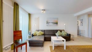 uma sala de estar com um sofá e uma mesa em FeWo in direkter Strandlage mit Balkon und Meerblick, Dünenresidenz Prora-App 111 em Binz
