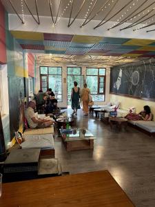 um grupo de pessoas sentadas numa sala com mesas em The VOID - Dharamkot em Dharamshala