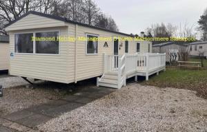 a small white trailer with a porch and a staircase at Caravan Marton Mere Blackpool in Weeton