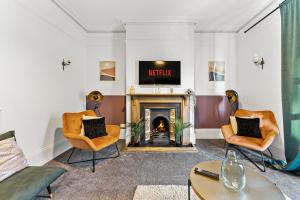 a living room with a fireplace and two chairs at Lovely Central Loughborough Abode - Games Room in Loughborough