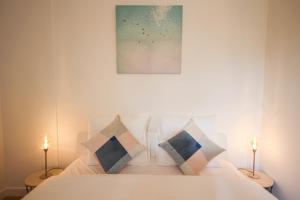 um quarto com uma cama branca com almofadas e um quadro em Fully-equipped apartment in city center + parking em Lille