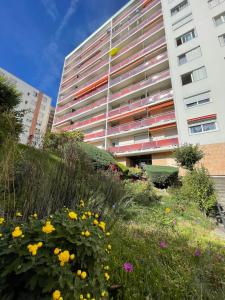 um edifício alto com um jardim em frente em Les Dômes du Parc 4e App T3 et T1 proche de toutes commodités em Clermont-Ferrand