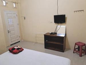 a bedroom with a bed and a television and a stool at OYO 93590 Penginapan Palapa 10 Syariah in Bandar Lampung