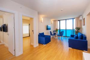 a living room with blue couches and a table with chairs at ORBI CiTY-sea view aparthotel in Batumi