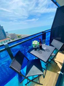 uma mesa com uma garrafa de vinho e flores numa varanda em ORBI CiTY-sea view aparthotel em Batumi