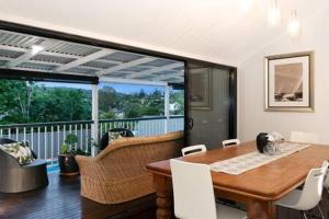 une salle à manger avec une table et un balcon dans l'établissement The Indooroopilly Queenslander - 4 Bedroom Family Home - Private Pool - Wifi - Netflix, à Brisbane