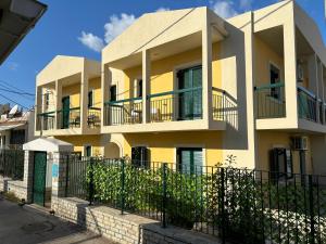 a yellow building with balconies and a fence at Nelly's Luxury Suites in Kassiopi