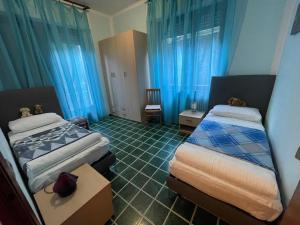 two beds in a room with blue curtains at Casa Variante in Cannobio