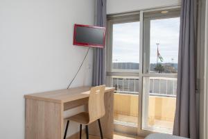 Habitación con escritorio, TV y ventana. en Pension Cuatro Vientos, en Cuevas del Almanzora