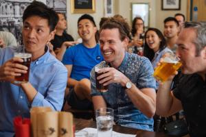 Eine Gruppe von Menschen, die an einem Tisch sitzen und Bier trinken. in der Unterkunft St Christopher's Liverpool Street in London