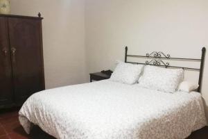 1 dormitorio con 1 cama blanca y armario de madera en Casa rural Los Barreros en Ciudad-Rodrigo