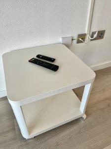 una mesa blanca con dos mandos a distancia. en Apartamento con vistas al mar y plaza aparcamiento, en Chilches