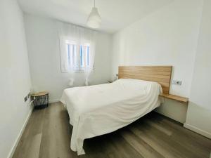 um quarto com uma cama com lençóis brancos e uma janela em Apartamento con vistas al mar y plaza aparcamiento em Chilches
