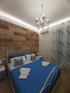 a blue bed in a room with a brick wall at Casa vacanze - "O Tunnu" in Avola