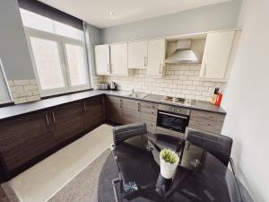 a kitchen with a table and two chairs in it at 3 Bedroom Apartment in the Heart of Newcastle - Modern - Sleeps 6 in Newcastle upon Tyne