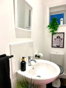 a white bathroom with a sink and a toilet at Elegant 3 bed flat with Parking in Portsmouth
