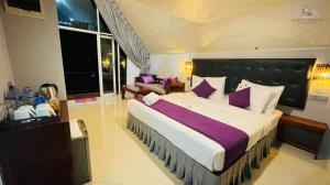 a large bedroom with a large bed with purple pillows at Almost Heaven in Talawakele