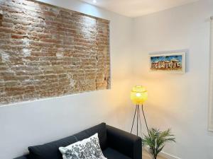 ein Wohnzimmer mit einer Backsteinwand und einer Couch in der Unterkunft Apartamento al lado de la playa in Barcelona