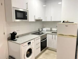 eine Küche mit weißen Schränken, einer Waschmaschine und einem Trockner in der Unterkunft Apartamento al lado de la playa in Barcelona