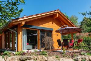 uma casa com um pátio com um guarda-sol e cadeiras em Haus Sternenblick em Drachselsried