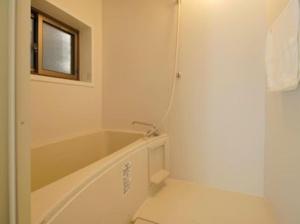 baño blanco con bañera y ventana en (旧信濃Natural)新規オープン！深呼吸したくなるゲストハウス。長野駅前徒歩8分！ en Nagano