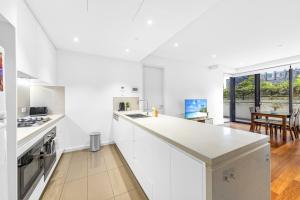a white kitchen with white cabinets and a table at Super comfy 2B Apt in Burwood in Sydney