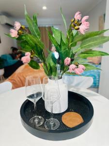 a tray with two glasses and a vase with flowers at Happy Guest house in Newcastle in Minmi