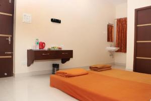 una camera da letto con un letto con un lenzuolo arancione e un tavolo di Elgozo Hotel Dreams Parasise a Yercaud