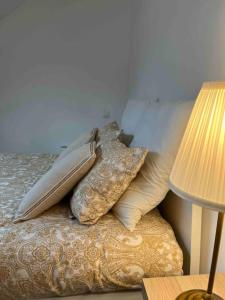 a pile of pillows on a bed next to a lamp at Duplex Place du Martroi in Orléans