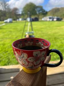 a cup of coffee sitting on a table with a field at Safari Tent in Pentewan
