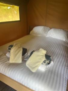 Una cama con sábanas blancas y toallas. en Safari Tent, en Pentewan