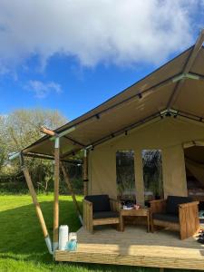a tent with chairs and a table in a yard at Safari Tent in Pentewan