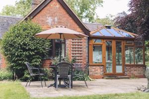 a table and chairs with an umbrella in front of a house at Detached homely bungalow with open fireplace in Priors Marston