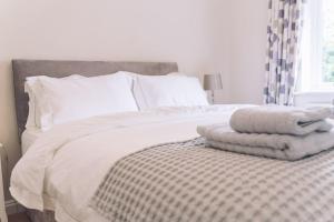 Schlafzimmer mit einem Bett mit weißer Bettwäsche und Kissen in der Unterkunft Detached homely bungalow with open fireplace in Priors Marston